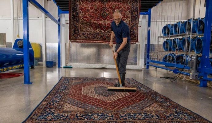 A person is cleaning a rug.