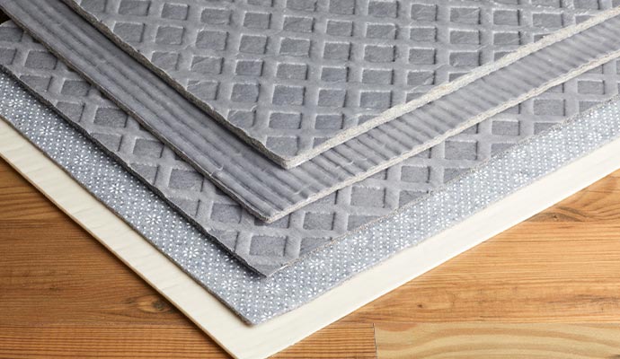 Layered gray rug pads with textured surfaces on a wooden floor