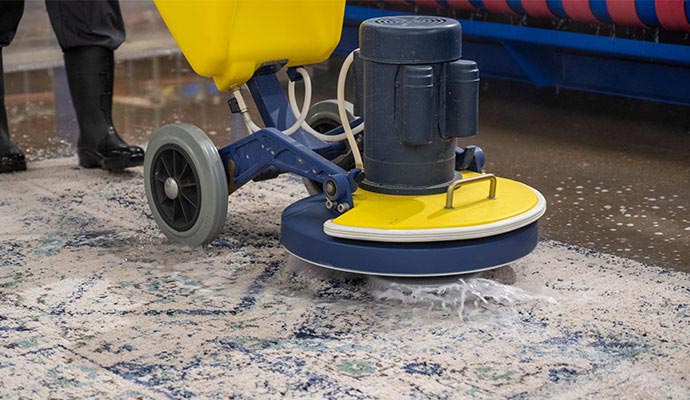 Industrial rug scrubbing machine cleaning patterned rug