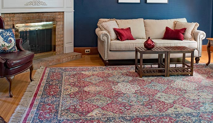 Large oriental rug in a living room with a sofa fireplace and coffee table