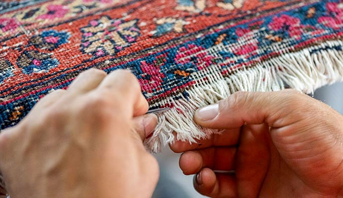 Expert repairing rug fringe to restore original look