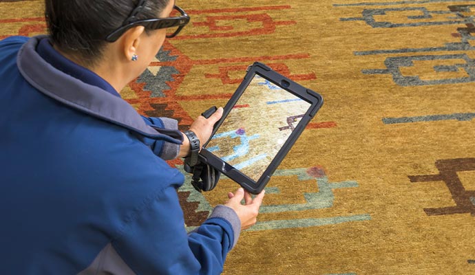 Professional inspecting rug with tablet