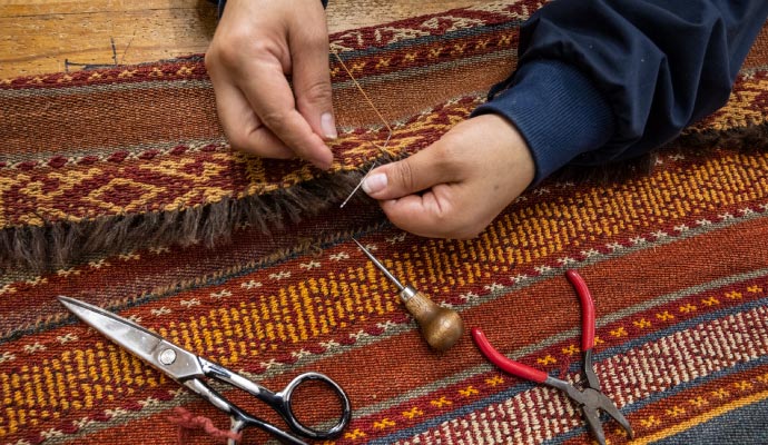 Expert repairing rug fringe to restore original look