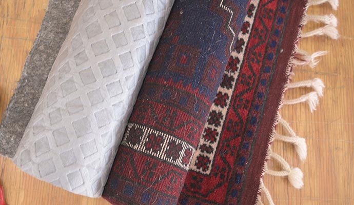 White rug pad placed underneath a patterned area rug on a wooden floor