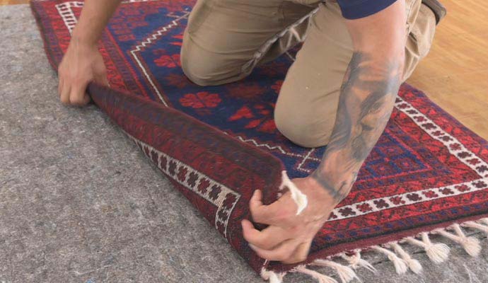 Technician installing an area rug over a felt rug pad