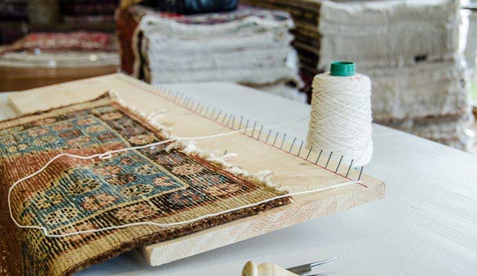 Oriental rug on wooden loom board for fringe reconstruction