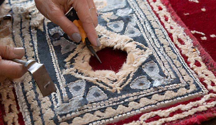 Specialist repairing hole and fiber damage on embroidered rug
