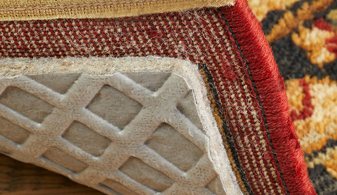 A rug lifted to show the pad underneath