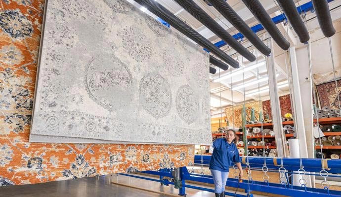 Technician operating hanging rug system in a professional cleaning facility