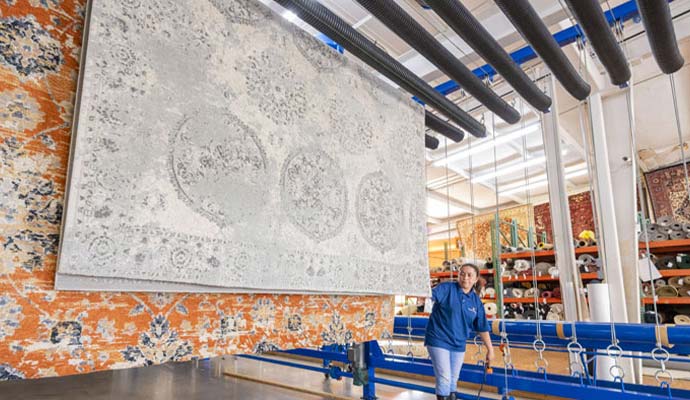 Technician hanging large area rugs on drying racks in a cleaning facility