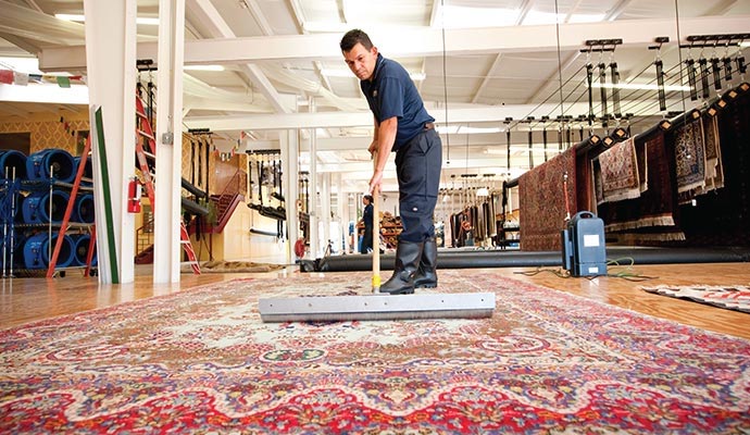 Technician squeegeeing a large oriental rug in a cleaning facility