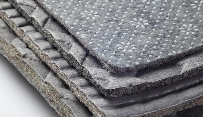 Close-up of stacked textured rug pad samples in gray tones
